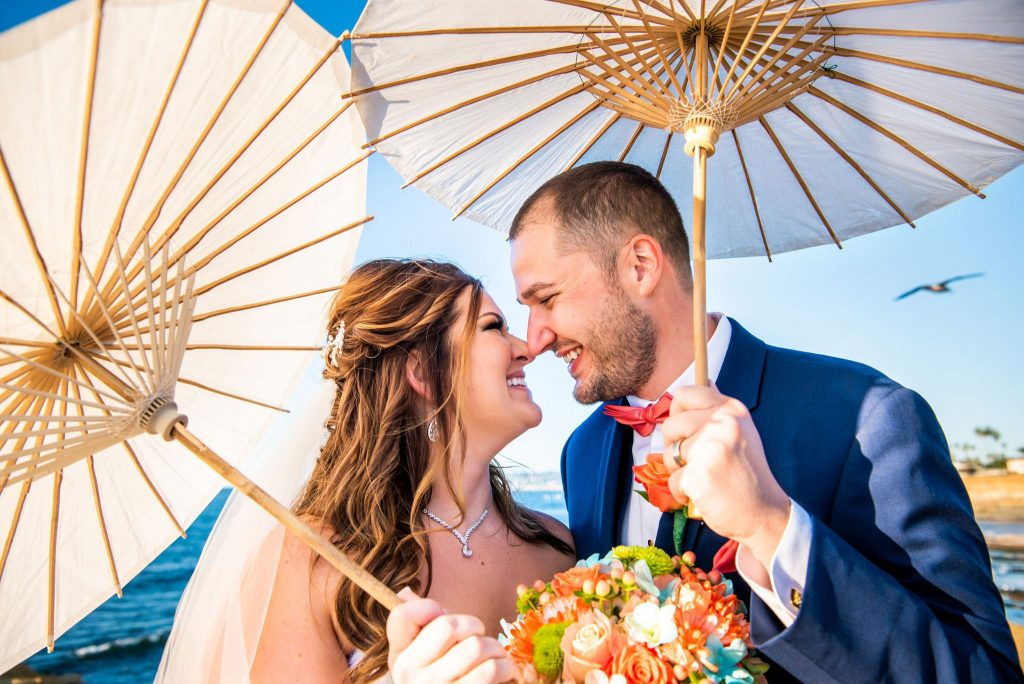 eloping couple smiling under decorative umbrellas