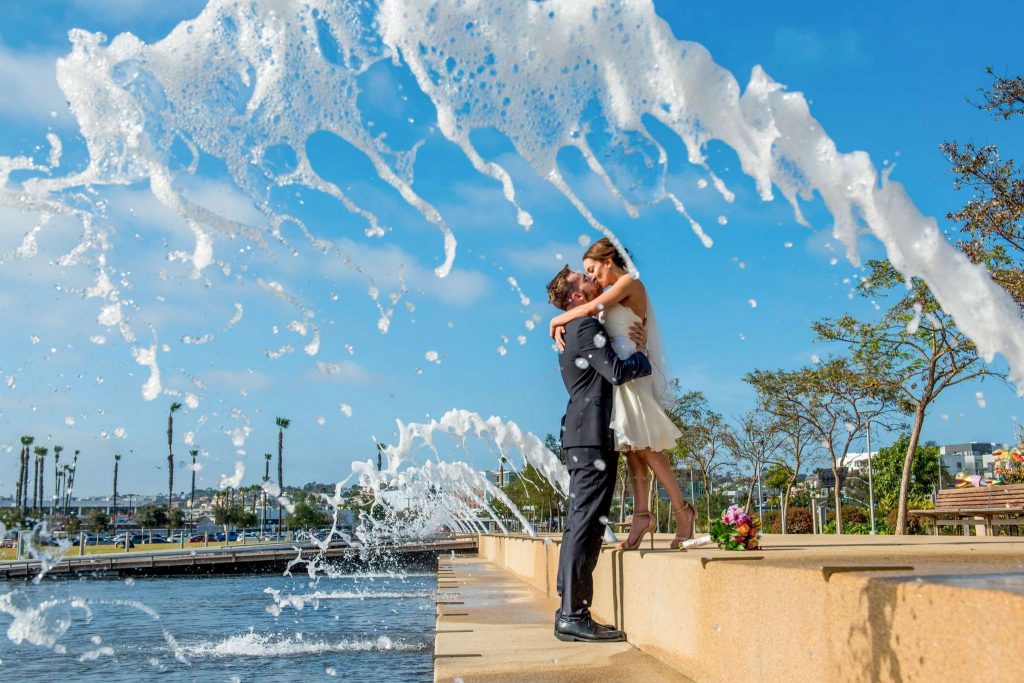 eloping couple standing between spraying fountain jets